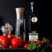 Fresh vegetables and olive oil with pepper mills displayed attractively.