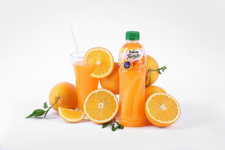 Orange juice bottle with fresh oranges and glass.
