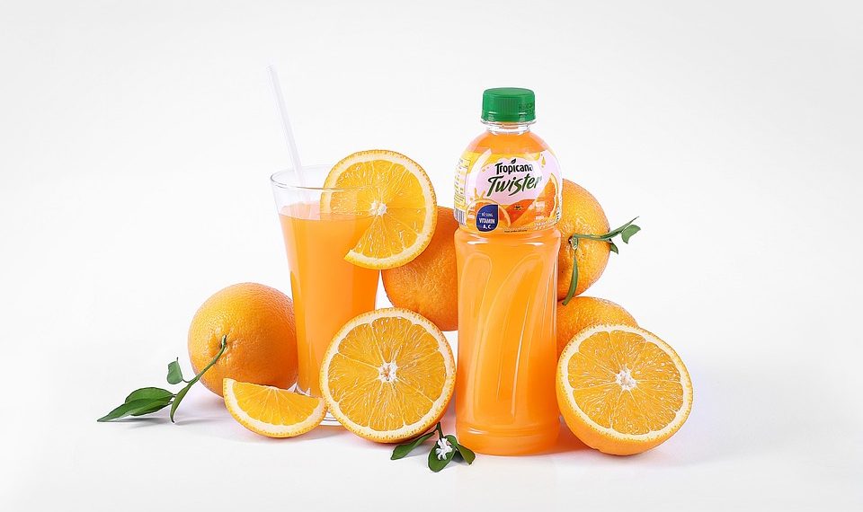 Orange juice bottle with fresh oranges and glass.