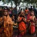 Women participating in a traditional prayer ceremony during a vibrant festival.