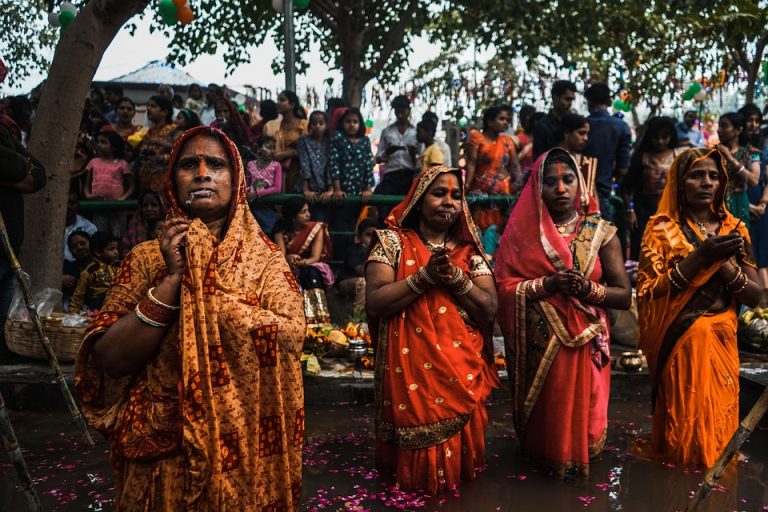 Women participating in a traditional prayer ceremony during a vibrant festival.