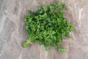 Fresh parsley bundle on a marble countertop.