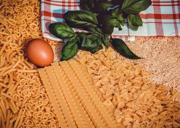Assorted pasta varieties with egg, basil, and towel.