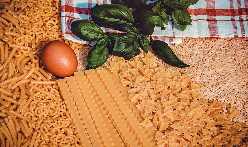 Assorted pasta varieties with egg, basil, and towel.