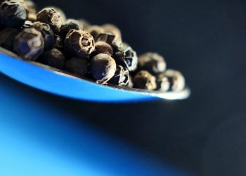 Black peppercorns on a spoon.