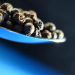 Black peppercorns on a spoon.