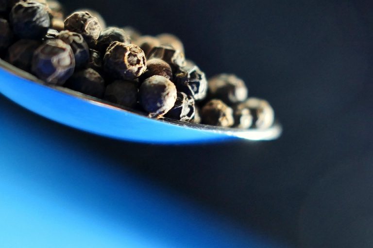 Black peppercorns on a spoon.