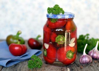Jar of pickled tomatoes with parsley and garlic cloves.