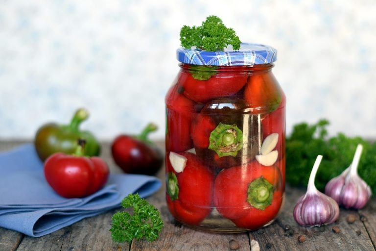 Jar of pickled tomatoes with parsley and garlic cloves.