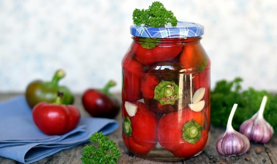 Jar of pickled tomatoes with parsley and garlic cloves.