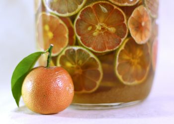 Tangerine and citrus slices in infused drink jar.