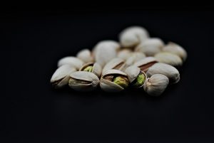Pistachios against a black background, nuts partially open.