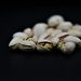 Pistachios against a black background, nuts partially open.