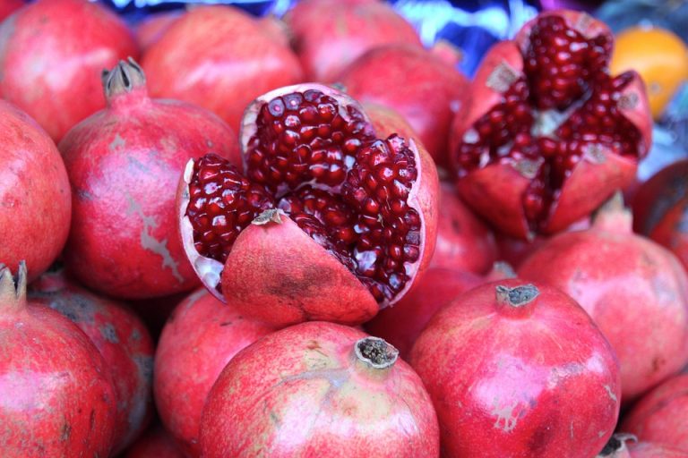 Pomegranate display with open fruit showing seeds.