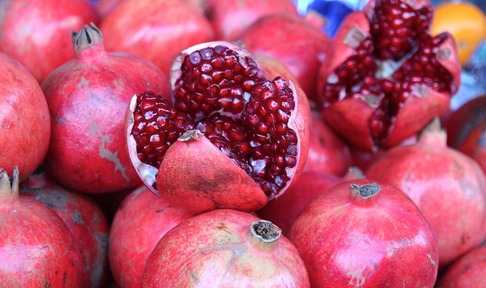Pomegranate display with open fruit showing seeds.
