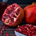 Fresh pomegranate and juice with seeds on dark table.