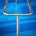 Stainless steel pool handrail over textured blue swimming pool cover.