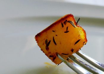 Roasted potato cube with herbs on a fork.