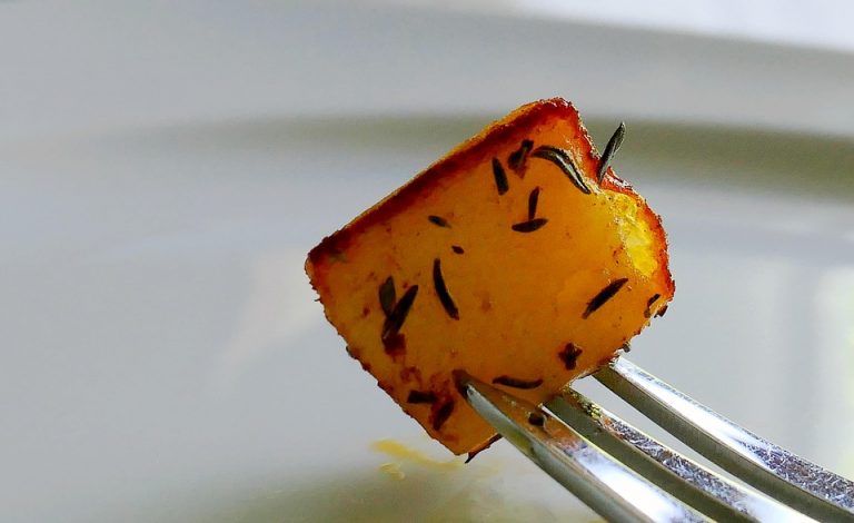 Roasted potato cube with herbs on a fork.