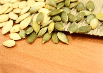 Pumpkin seeds scattered on a wooden surface.