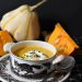 Creamy pumpkin soup in a decorative bowl with fresh pumpkins.