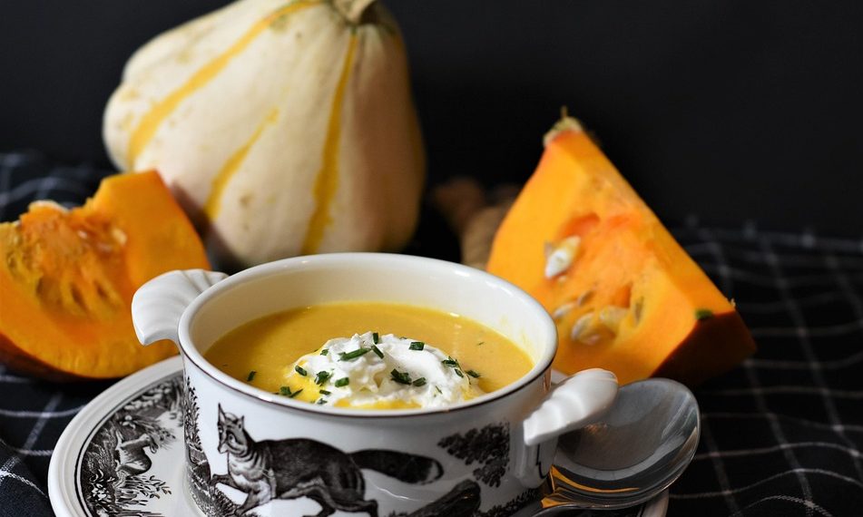 Creamy pumpkin soup in a decorative bowl with fresh pumpkins.