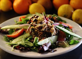 Fresh mixed salad with cucumbers, tomatoes, and grains.