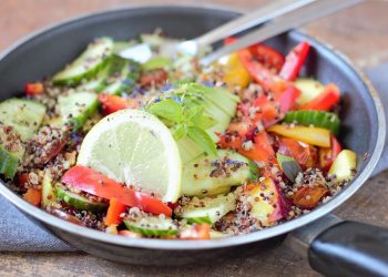 Fresh quinoa salad with cucumber, tomato, bell pepper, and lemon slices.