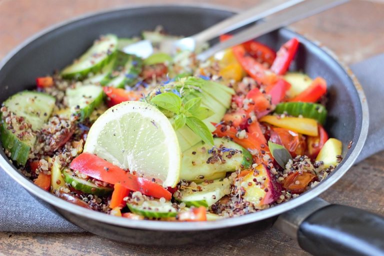 Fresh quinoa salad with cucumber, tomato, bell pepper, and lemon slices.
