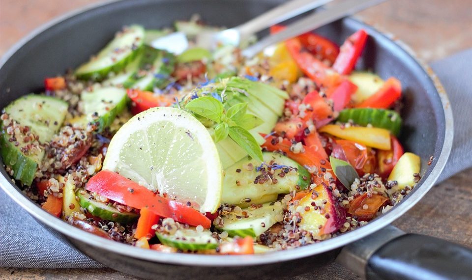 Fresh quinoa salad with cucumber, tomato, bell pepper, and lemon slices.
