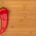 Red chili pepper on wooden cutting board.