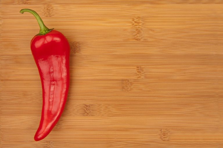 Red chili pepper on wooden cutting board.