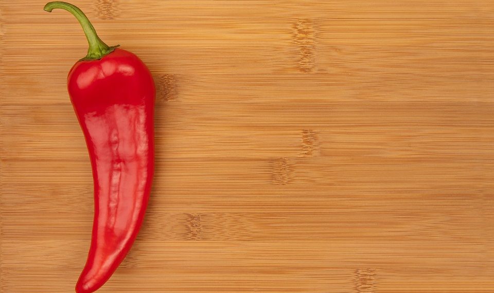 Red chili pepper on wooden cutting board.