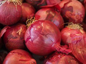 Red onions with peels intact, fresh and ready for cooking.