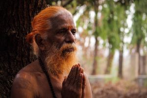 Praying elderly man with folded hands in contemplative meditation.