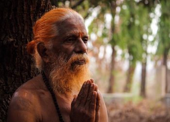 Praying elderly man with folded hands in contemplative meditation.