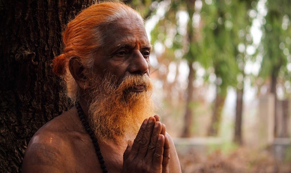 Praying elderly man with folded hands in contemplative meditation.