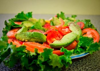 Fresh salad with lettuce, tomato, and avocado slices on a plate.