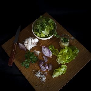 Fresh lettuce, garlic, and herbs on a wooden cutting board.
