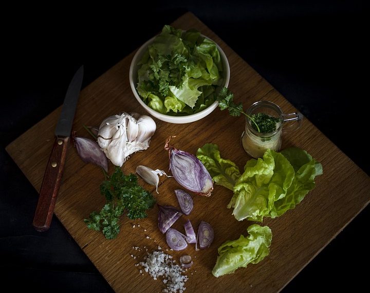 Fresh lettuce, garlic, and herbs on a wooden cutting board.