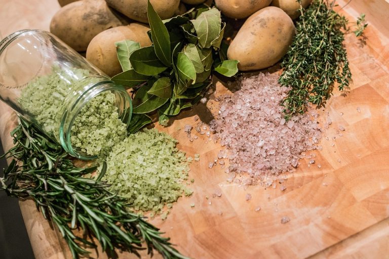 Herbs, spices, and potatoes on a wooden board.