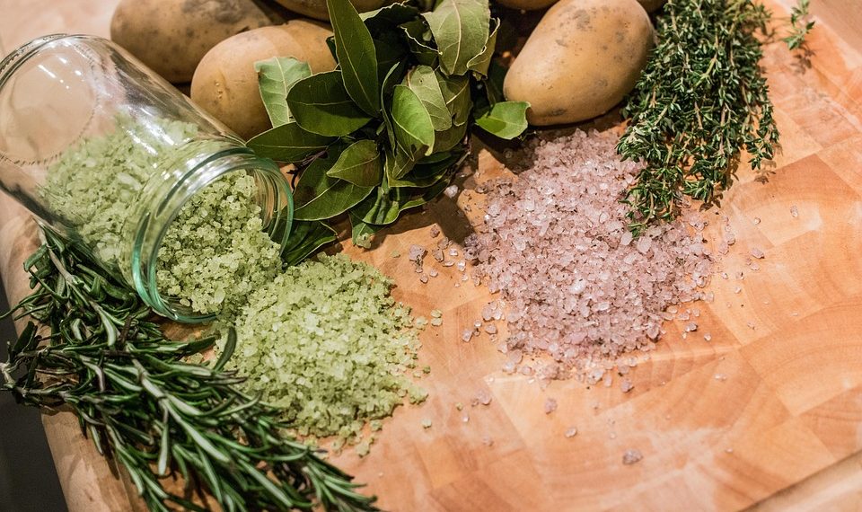 Herbs, spices, and potatoes on a wooden board.