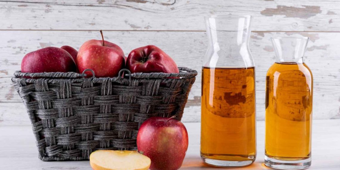 Basket of red apples with apple cider in bottles.