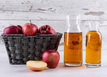 Basket of red apples with apple cider in bottles.