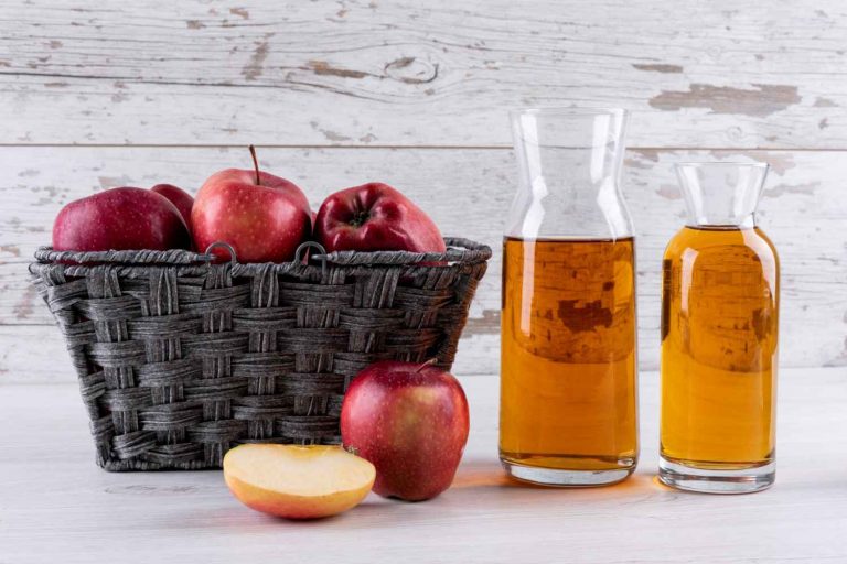 Basket of red apples with apple cider in bottles.