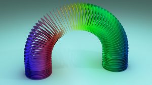 Colorful rainbow Slinky toy arched gracefully on a light blue background.