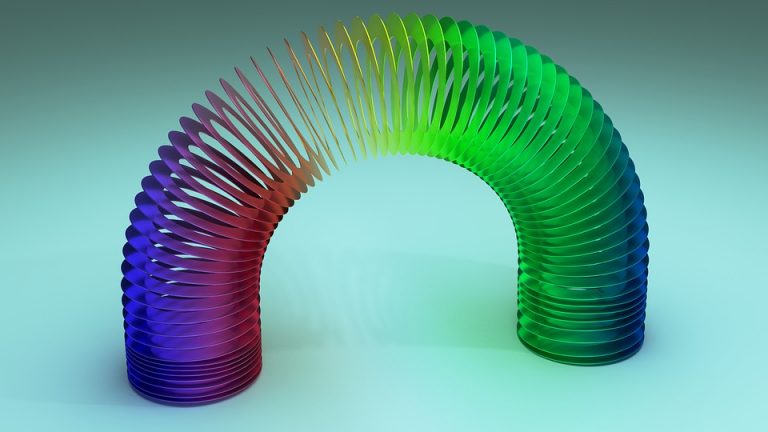 Colorful rainbow Slinky toy arched gracefully on a light blue background.