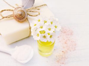 White flowers in a small jar beside natural soap and a feather.