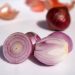 Sliced red onion halves and whole onion on white background.