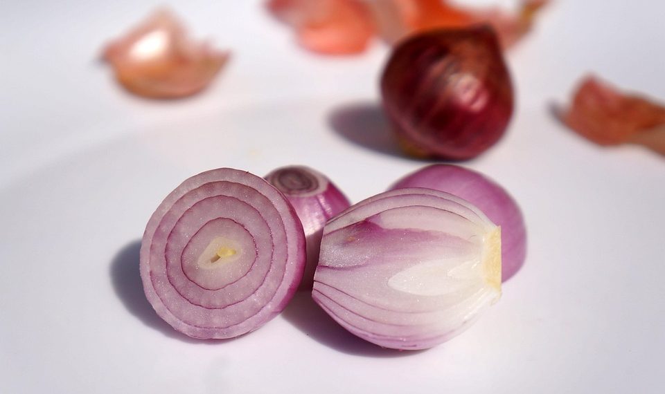 Sliced red onion halves and whole onion on white background.